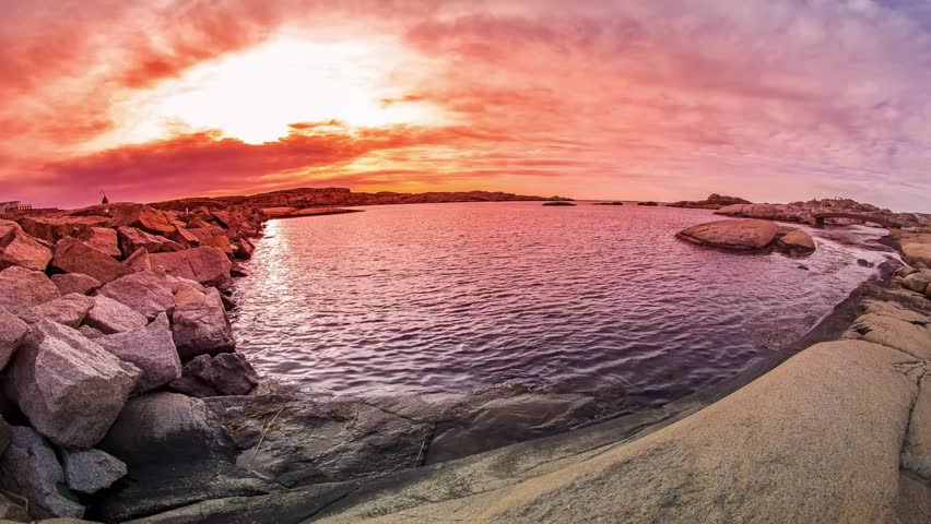 Vibrant Sunset over Rocky Coastline and Calm Ocean Waters