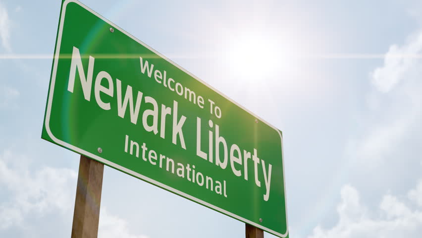 4k Welcome to Newark Liberty International Airport Green Road Sign and Airplane Flying Low Overhead with Landing Gear Down.