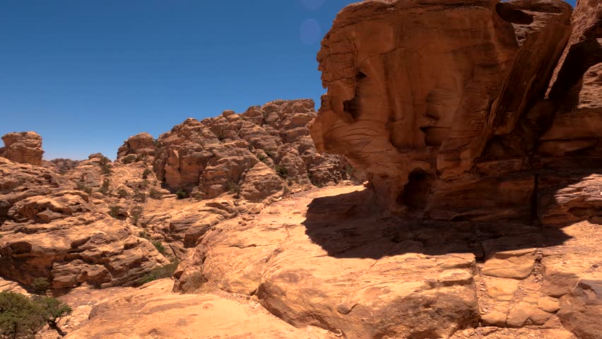Red sandstone rock formations and a desert canyon landscape under a clear blue sky in Jordan.