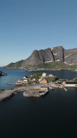 Discover a picturesque coastal village in Lofoten Norway, framed by towering mountains and serene waters. Perfect for showcasing the beauty of nature and Norwegian architecture in a tranquil setting.