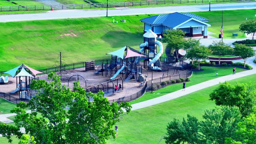 aerial footage of children playing on the playground Logan Farm Park with lush green trees and grass in Acworth Georgia USA