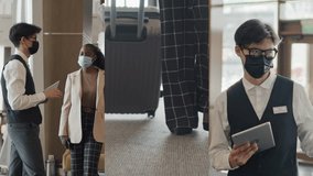 Split screen shot of young male Asian hotel worker in face mask greeting female African American tourist or business lady in lobby and providing necessary information - Powered by Shutterstock - Get 15% off with code: PIKWIZARD15