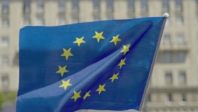 European Union flag attached to a pole, waving in the wind in an urban setting, possibly during a peaceful protest. Symbol of unity, democracy, and European identity. - Powered by Shutterstock - Get 15% off with code: PIKWIZARD15