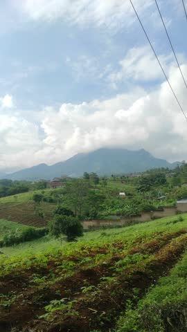 View of Mountains and Fields Under Blue Sky and White Clouds.