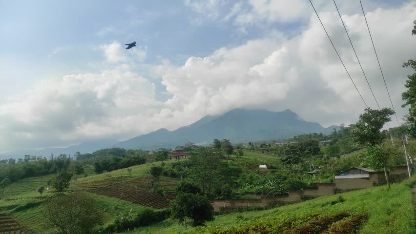 View of Mountains and Fields Under Blue Sky and White Clouds.
