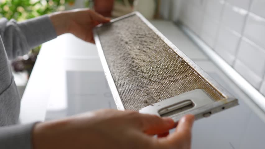Dirty greasy kitchen hood filter that not clean for long time. Man hands check broken dirty grid, dust food grease accumulation, air quality risk, prevention of respiratory issue, maintenance neglect