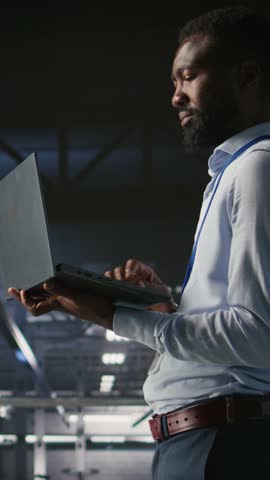 Vertical video Technicians on data center industrial platform analyzing performance outputs after completing software updates. Server hub engineering team finetuning server rig configurations, camera