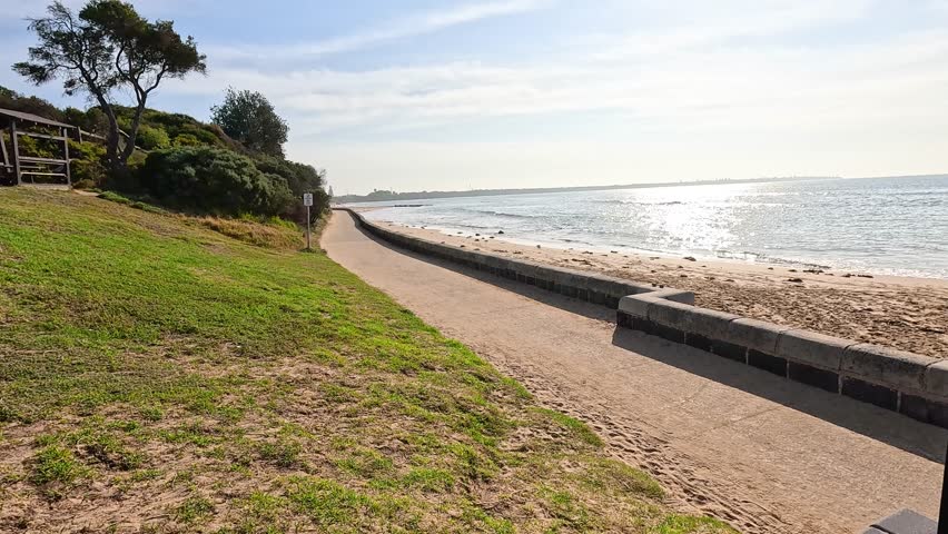 A scenic beach pathway at Point Lonsdale, Victoria, Australia, under clear skies with vibrant greenery and ocean views