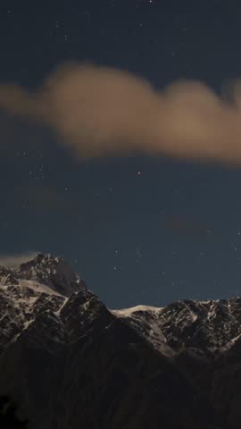 A serene night sky with stars above a snow-capped mountain range, captured with minimal camera movement