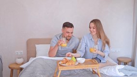 Married couple enjoying romantic breakfast in bed in the morning at home with croissants and orange juice - Powered by Shutterstock - Get 15% off with code: PIKWIZARD15