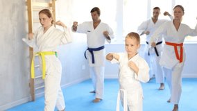 Kid boy and his family repeat movements and learn fighting techniques during martial arts lesson. Experienced man unrecognizable instructor conducts personal karate training for large family - Powered by Shutterstock - Get 15% off with code: PIKWIZARD15
