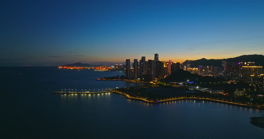 Aerial shot of a city skyline with modern buildings along the coast at night in Shenzhen, China.