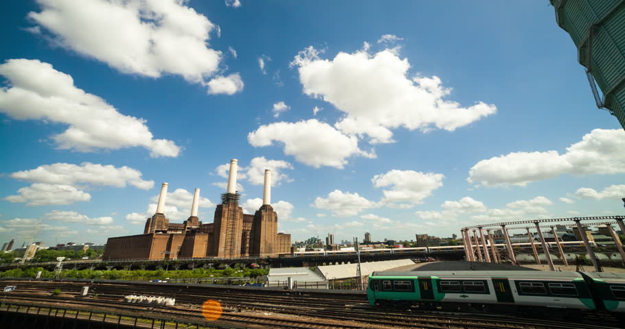 A static time-lapse of a power station in London with fast-moving clouds and trains running in the foreground.
