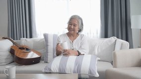 Senior Woman Relaxing at Home. Happy Asian Elderly Enjoying Morning Coffee on Sofa in Living Room with Warm Light and Calm Atmosphere. - Powered by Shutterstock - Get 15% off with code: PIKWIZARD15