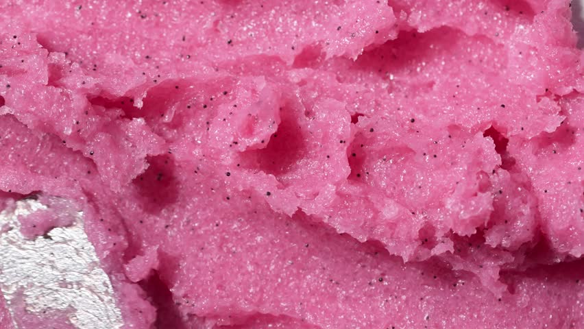 Texture of pink raspberry scrub. Fruit exfoliation scrubber for body and face in SPA. Body care scrub background for design.