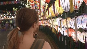Female traveler wandering moonlit path, surrounded by glowing silk lanterns adorning traditional fence, experiencing nighttime cultural immersion - Powered by Shutterstock - Get 15% off with code: PIKWIZARD15