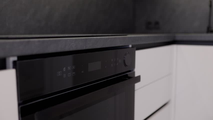 This kitchen showcases a modern design with a sleek black oven and minimalist cabinetry. Perfect for those who appreciate efficiency and style in cooking spaces.