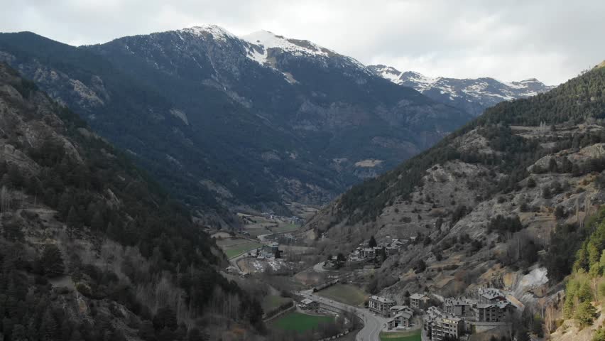 Aerial view of Andorran mountain valley with small village nestled among snow-capped peaks. Scenic Pyrenees landscape, travel destination, Andorra