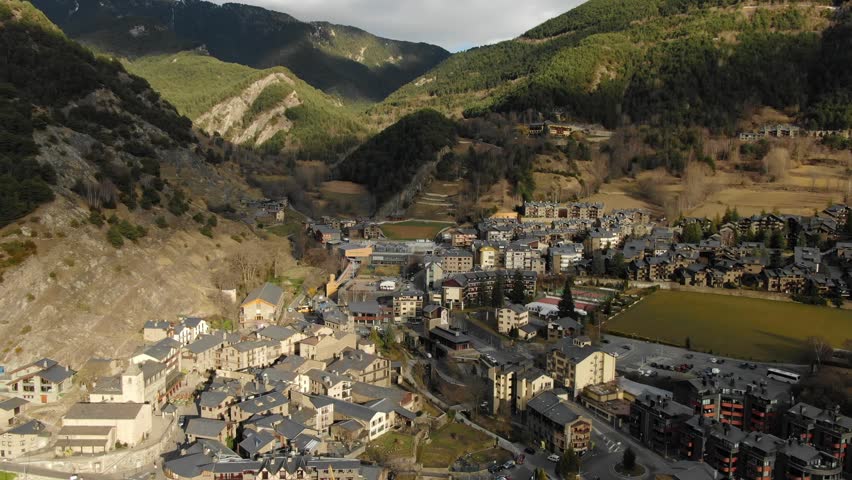 Aerial perspective of Andorran town in mountain valley with forest and fields. European alpine community, scenic travel and nature overview