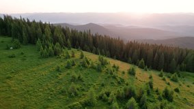 Aerial view of campsite on grassy hillside, with tents scattered amidst lush greenery and small trees. Golden hues of sunrise. In distance, layers of rolling mountains fade into horizon. - Powered by Shutterstock - Get 15% off with code: PIKWIZARD15