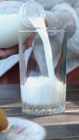 Vertical video. Woman drinking milk. Pouring milk into transparent glass