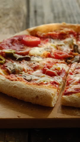 Vertical video. Hand taking slices of baked homemade pizza