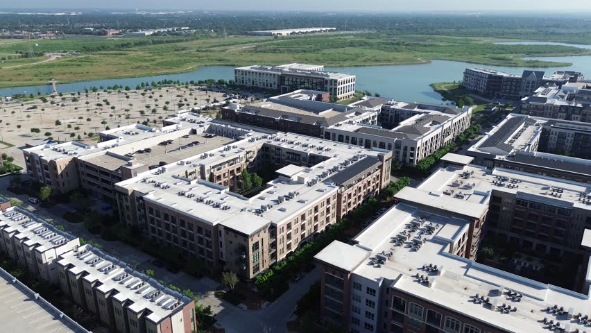Flat roof commercial HVAC unit packages at modern lakeside apartment building complex with tree lined street, walking trails, pool, master-planned Cypress Waters suburb Dallas Fort Worth metroplex. US