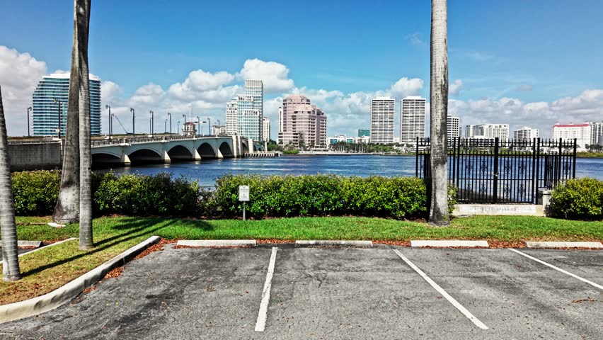 Aerial: cityscape from parking lot with Royal Park Bridge, One Flagler and Phillips Point building during the day in West Palm Beach, Florida, USA, establishing drone shot