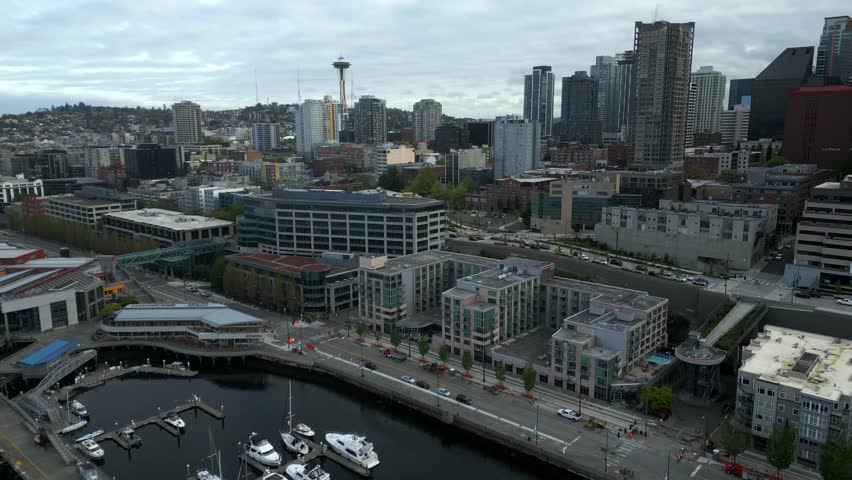 Panoramic view of Seattle Waterfront and pier with dense cityscape backdrop and Space Needle spire at Seattle, Washington, USA - aerial drone shot