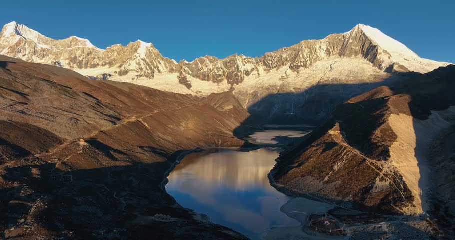 Aerial footage of beautiful snow capped mountain and lake sunrise landscape in Tibet, China