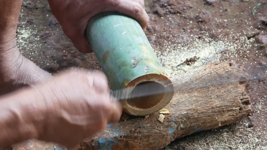 a worker cuts bamboo using a machete