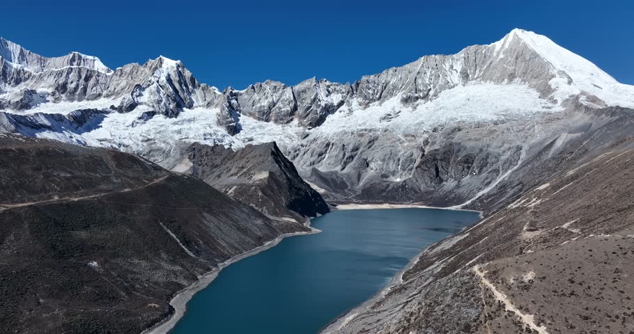 Aerial footage of beautiful snow capped mountain and lake sunrise landscape in Tibet, China