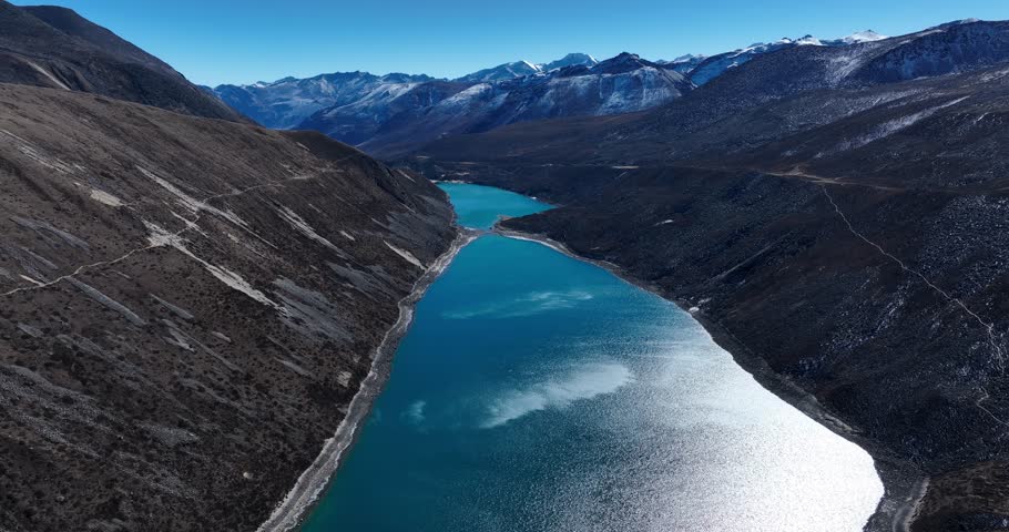 Aerial footage of beautiful snow capped mountain and lake sunrise landscape in Tibet, China