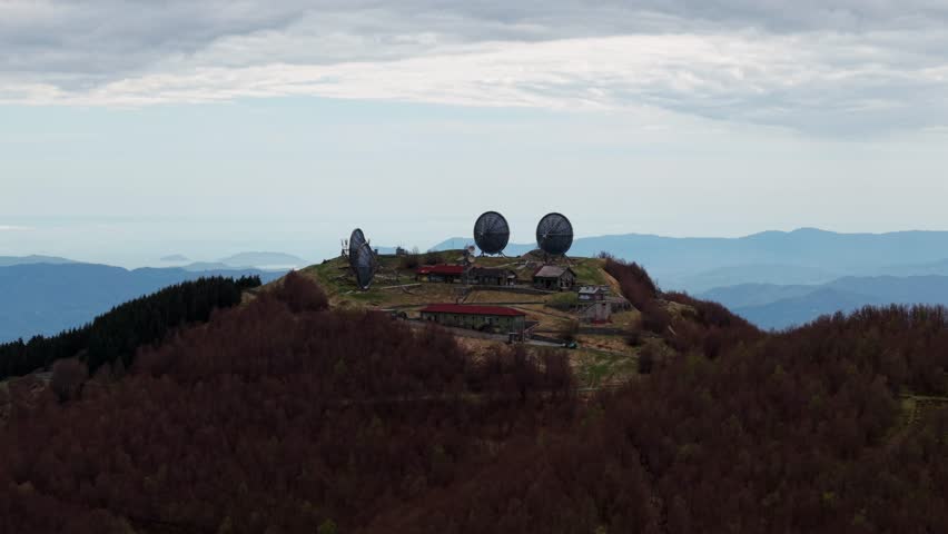 Old radar station on mountain top, wide aerial with moody weather and soft light