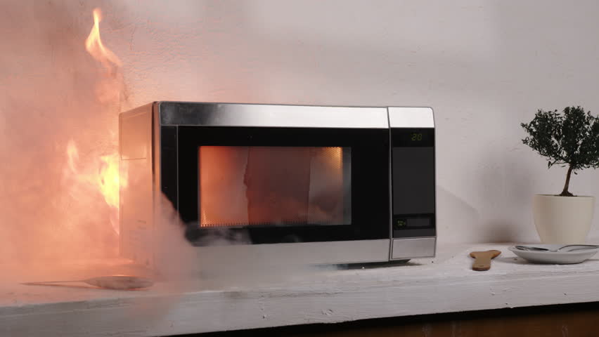 Microwave oven smokes and bursts into flames after turning on electricity, starting house fire.