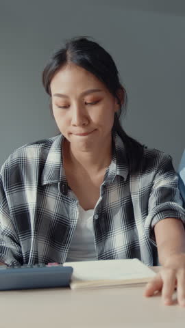 Vertical Screen : Stress asia couple man woman use calculator for calculate family budget, debts, monthly expenses during financial economic crisis at home. Marriage money trouble budget plan concept.