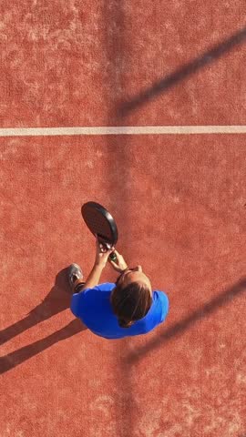 Vertical, Top view of a professional paddle tennis player who is playing a match on an outdoor court.