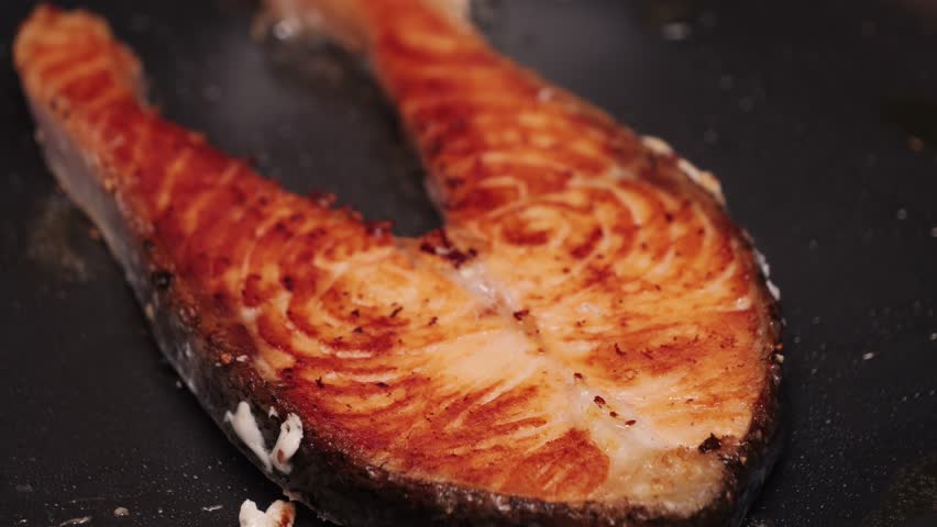 Improperly cooked salmon fillets at home, overcooked fish on a frying pan, close-up. High quality 4k footage