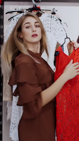 Business woman chooses clothes in the store, admiring herself in front of a mirror, smiles. Shopping in a stylish clothing store. slow motion