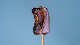 Marshmallow on Stick Burning, Covered with Black Crust, Sugar Bubbling and Smoking. Close-Up Roasting Candy on a Blue Background - Powered by Shutterstock - Get 15% off with code: PIKWIZARD15