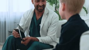 Joyful Indian Pediatric professional engaging young boy patient through digital tablet during medical consultation, wearing white medical coat in clinical setting, giving high five  - Powered by Shutterstock - Get 15% off with code: PIKWIZARD15