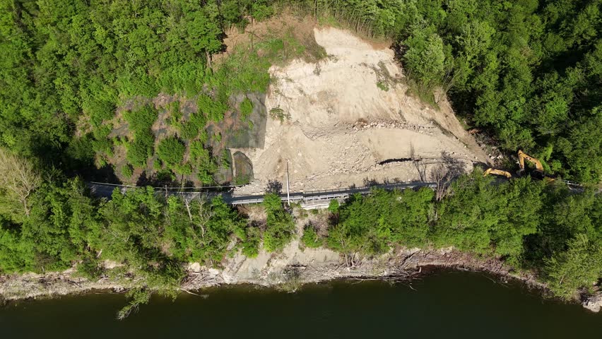 Mountain terrain landslide due to spring heavy rains blocks provincial road 21 near Vernasca Mignano dam and basin with heavy machinery clearing debris, PC, Italy