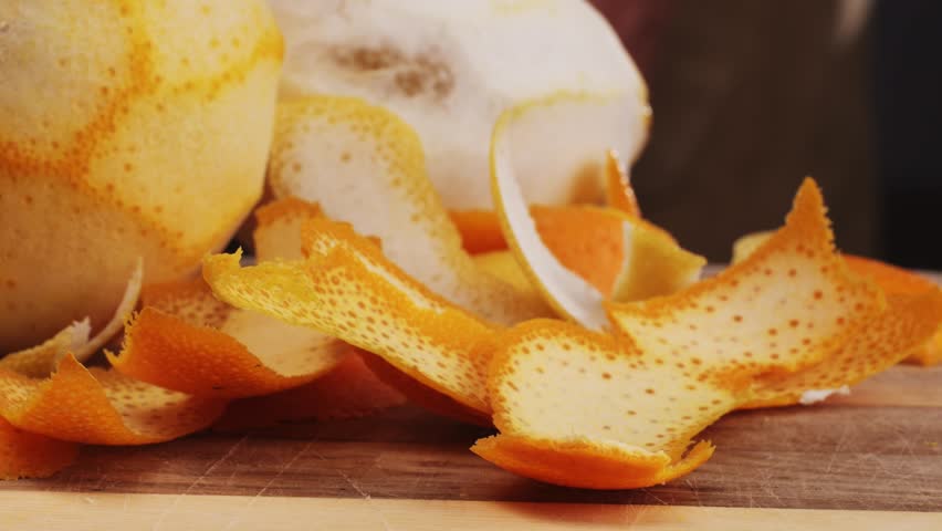 bartender makes a cocktail in a glass with orange peel, barman peeling orange or lemon. 