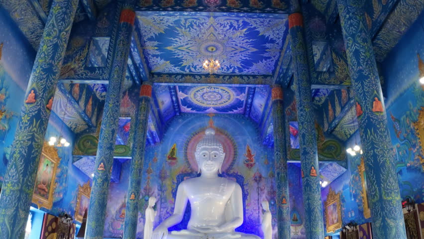 The painted ceiling of the Blue Temple in Chiang Rai, Thailand, adorned with intricate blue designs and golden frames with images of Buddha and detailed patterns.
