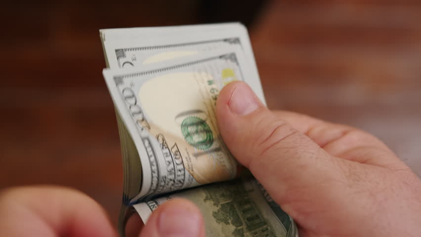 Dollar money in male hands counting their amount close-up.