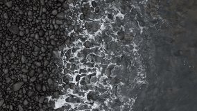 Aerial Top Down: Dark Smooth Pebbles and White Sea Foam on Rocky Shore.Moody Coastal Scene: Dark Pebbles Washed by Swirling Sea Water, Top View. Black Pebble Beach Detail. - Powered by Shutterstock - Get 15% off with code: PIKWIZARD15