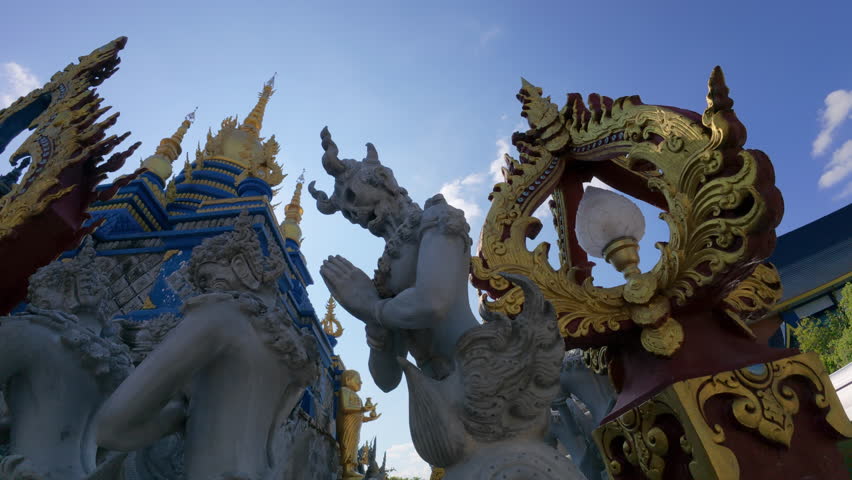 The painted ceiling of the Blue Temple in Chiang Rai, Thailand, adorned with intricate blue designs and golden frames with images of Buddha and detailed patterns.