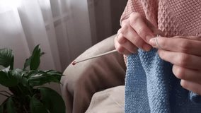 A woman is sitting in a room knitting with knitting needles . Making hand - knitted items . - Powered by Shutterstock - Get 15% off with code: PIKWIZARD15