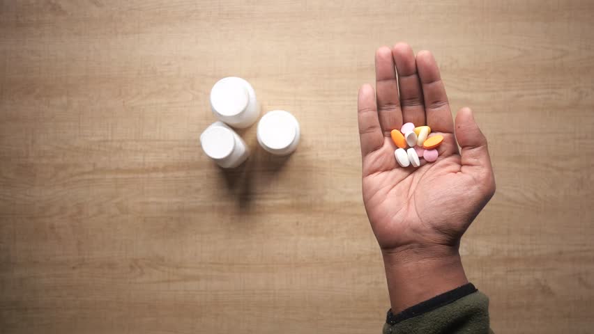 Individual Grasping a Variety of Medications with Various Pill Bottles