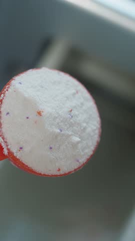 Laundry detergent powder in a measuring scoop